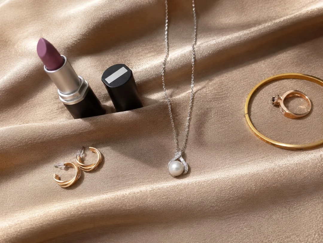 Pearl necklace and gold jewellery flatlay on champagne satin